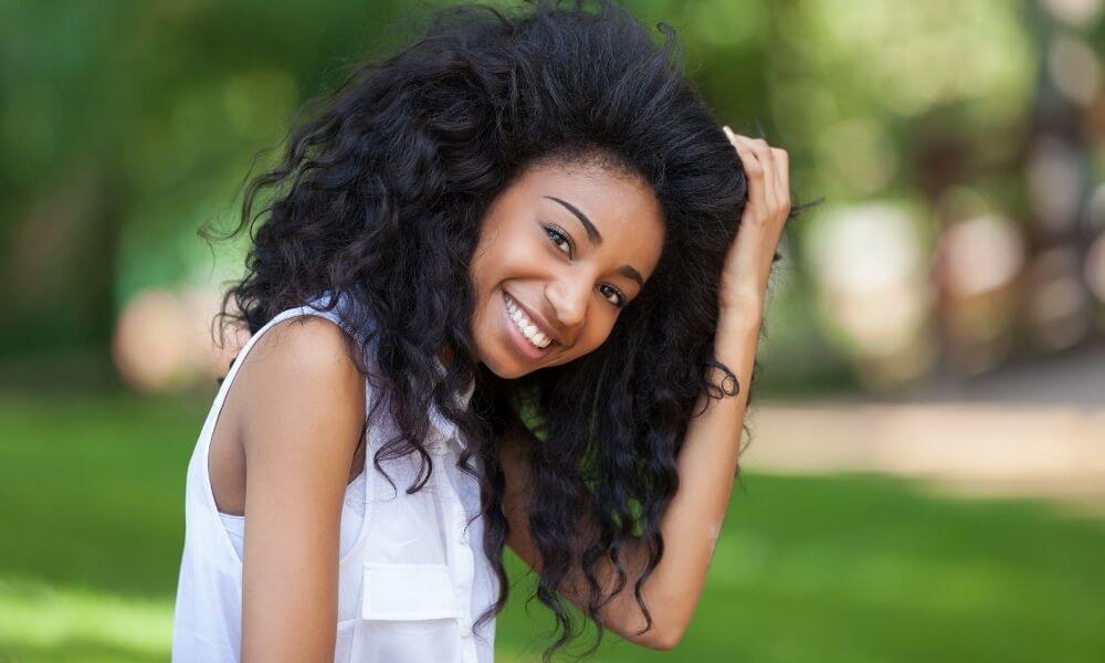 Schwarze Frau lächelt und fasst sich in die Haare
